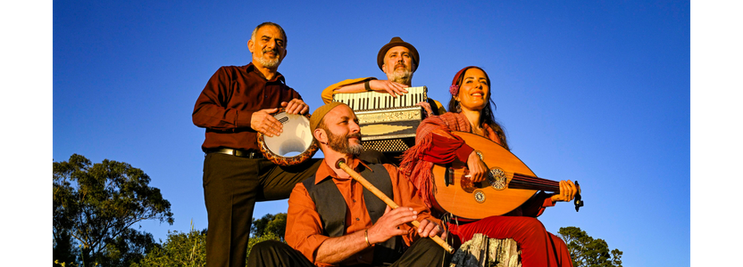 Three men and a woman holding instruments sitting on a tree stump